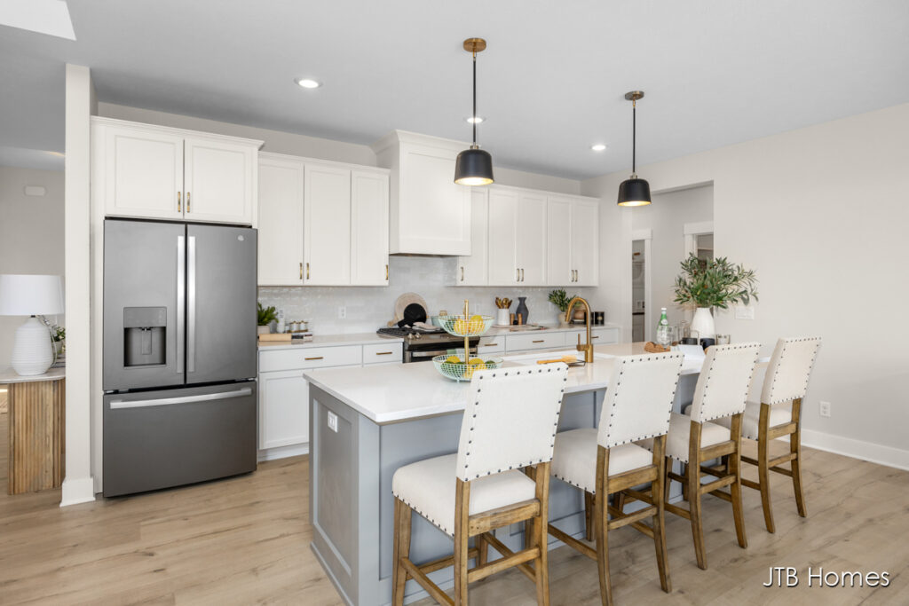 large kitchen with white cabinetry, large kitchen island, pendant lighting and white and wood bar stools