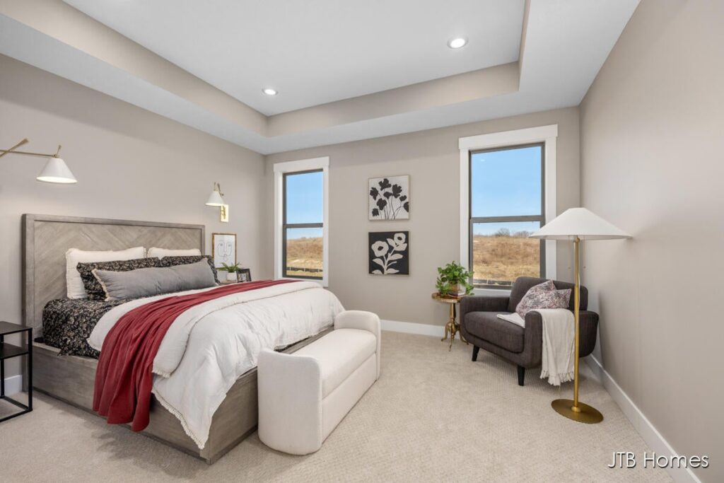 Chestnut owner's suite bedroom with tray ceiling, beige walls and two large windows